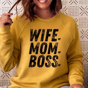 May include: A mustard yellow sweatshirt with the text "Wife Mom Boss" in black with a small heart after each word.