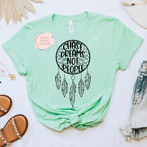 May include: A light green t-shirt with a black dreamcatcher design and the text "Chase Dreams Not People".