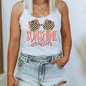 May include: A white tank top with a graphic of sunglasses with flowers and the text "Sunshine season".