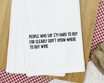 May include: White kitchen towel with black text that reads "PEOPLE WHO SAY I'M HARD TO BUY FOR CLEARLY DON'T KNOW WHERE TO BUY WINE"