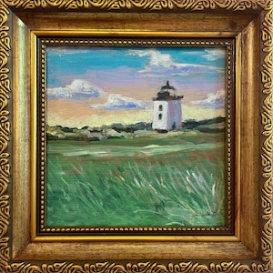 Puede incluir: Pintura enmarcada cuadrada de un faro sobre un campo de hierba bajo un cielo azul con nubes. El faro es blanco con la parte superior negra. El marco es dorado con detalles ornamentados. La pintura está firmada.