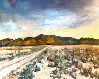May include: A painting of a dirt road leading towards a mountain range in the distance. The sky is a light blue with white clouds. The foreground is covered in green brush.