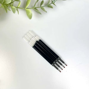 May include: Five black and silver ballpoint pen refills with red tips.