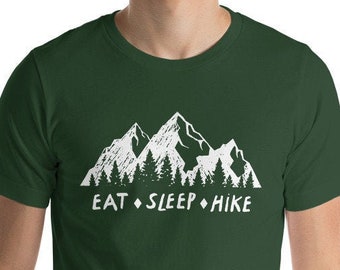 May include: A dark green t-shirt with a white graphic of mountains and trees. The text "EAT SLEEP HIKE" is printed below the graphic.