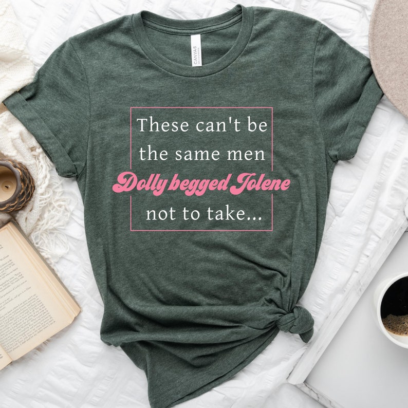 Pode incluir: Uma camiseta verde com o texto "These can't be the same men Dolly begged Jolene not to take..." impresso em branco. O texto "Dolly begged Jolene" est&aacute; em rosa e estilizado.