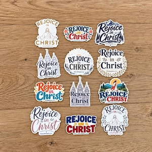 May include: A collection of twelve die-cut stickers featuring various artistic designs with the text Rejoice in Christ and Philippians 4:4. The stickers display diverse fonts, illustrations of religious figures, temple architecture, and floral motifs.