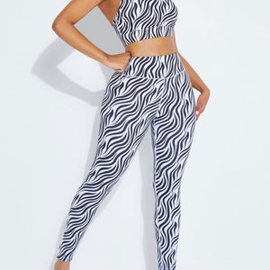 K&ouml;nnte beinhalten: Ein zweiteiliges Sport-Set mit einem schwarz-wei&szlig;en Zebramuster. Das Set besteht aus einem Sport-BH mit d&uuml;nnen Tr&auml;gern und einer hoch taillierten Leggings. Das Outfit ist f&uuml;r Fitnessaktivit&auml;ten konzipiert und besteht aus einem dehnbaren Material.