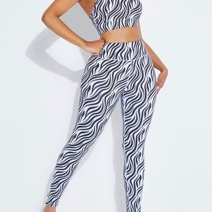 K&ouml;nnte beinhalten: Ein zweiteiliges Sport-Set, bestehend aus einem Sport-BH und Leggings. Das Set ist mit einem schwarz-wei&szlig;en Zebra-Streifenmuster versehen. Der Sport-BH hat einen Rundhalsausschnitt und d&uuml;nne Tr&auml;ger. Die Leggings sind hoch tailliert.