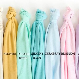 May include: Seven fabric swatches in various colors, including ivory, mustard, mint, and orchid, are displayed against a white background. Each swatch is knotted at the top, with color names printed below. The colors range from light to medium tones.