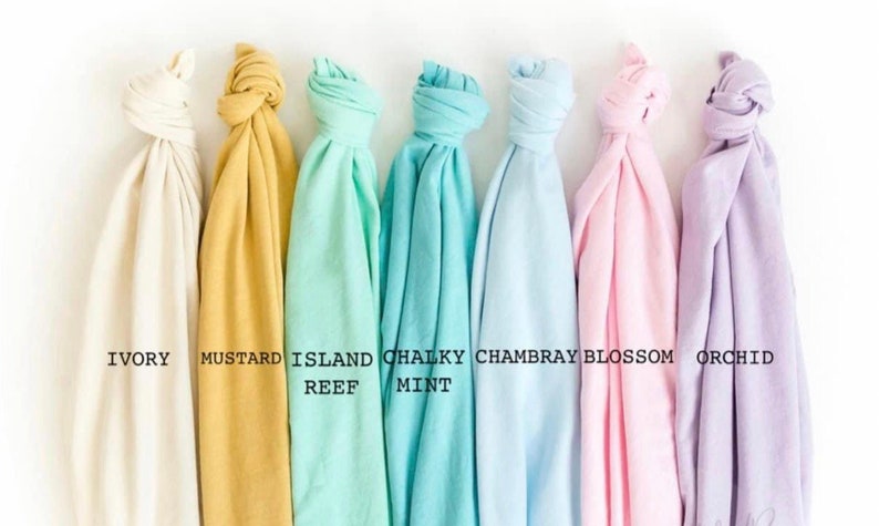 May include: Seven fabric swatches in various colors, including ivory, mustard, mint, and orchid, are displayed against a white background. Each swatch is knotted at the top, with color names printed below. The colors range from light to medium tones.