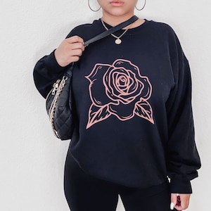May include: Black sweatshirt with a pink rose graphic design.