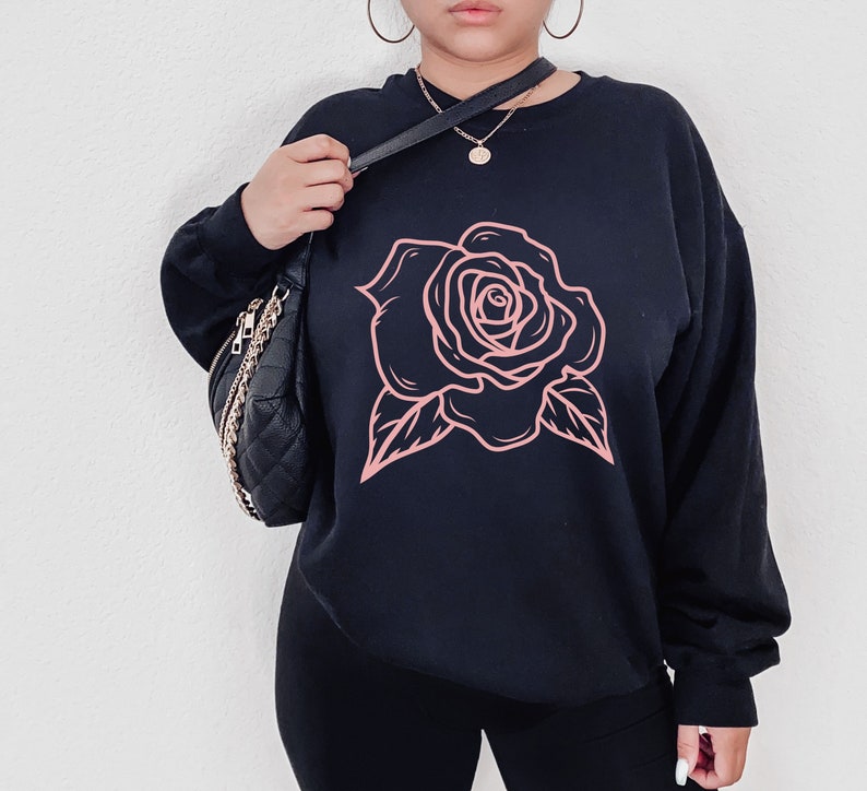 May include: Black sweatshirt with a pink rose graphic design.