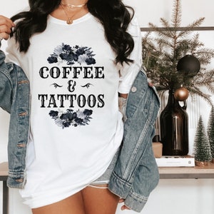 May include: White t-shirt with a black floral design and the text "COFFEE & TATTOOS".