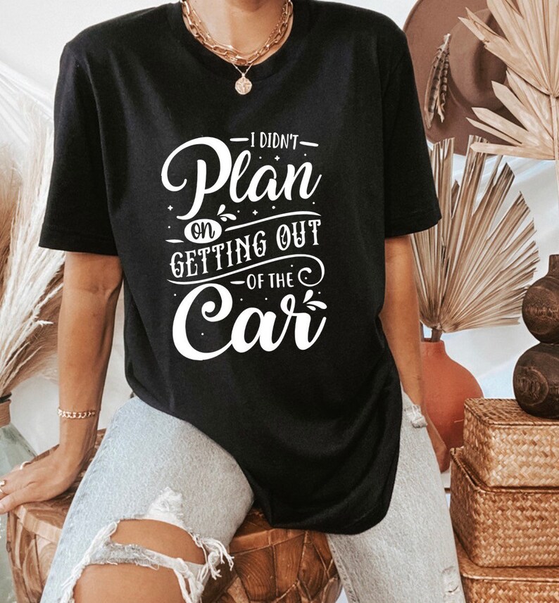 Może przedstawiać: Czarny T-shirt z białym napisem "Nie planowałem wysiadać z samochodu".