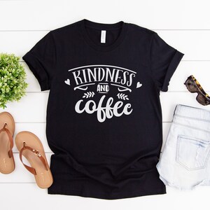 May include: Black t-shirt with white text that reads "kindness and coffee" with two small hearts on either side of the word "kindness".
