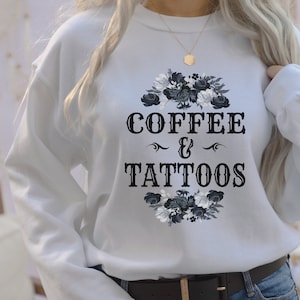 May include: White sweatshirt with a black floral design and the text "COFFEE & TATTOOS" in a vintage font.