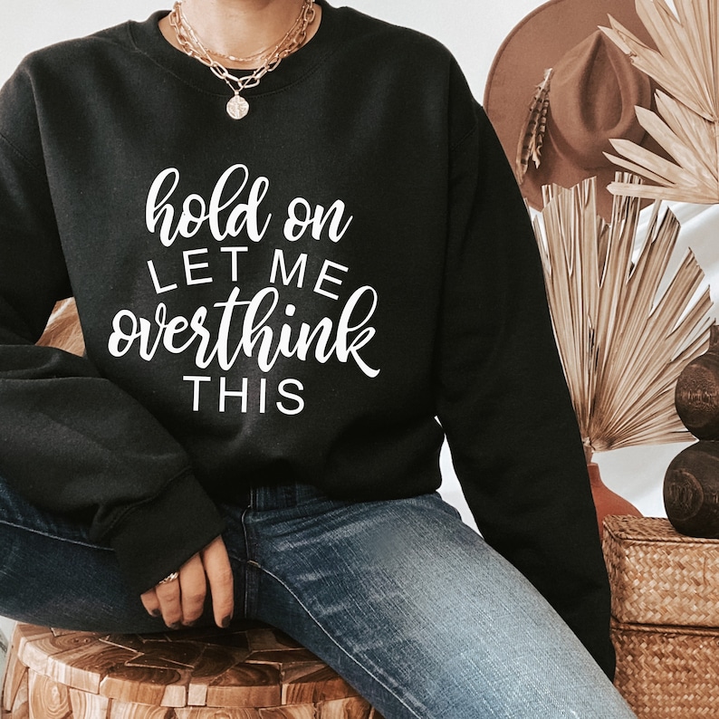 May include: Black sweatshirt with white text that reads "hold on let me overthink this".