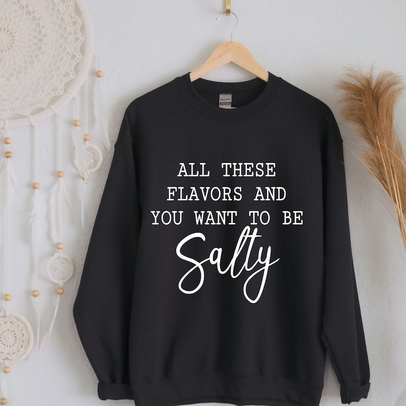 May include: Black sweatshirt with white text that reads "All these flavors and you want to be Salty".