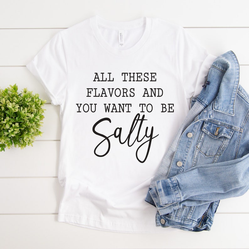 May include: White t-shirt with the text "All these flavors and you want to be Salty" in black lettering.