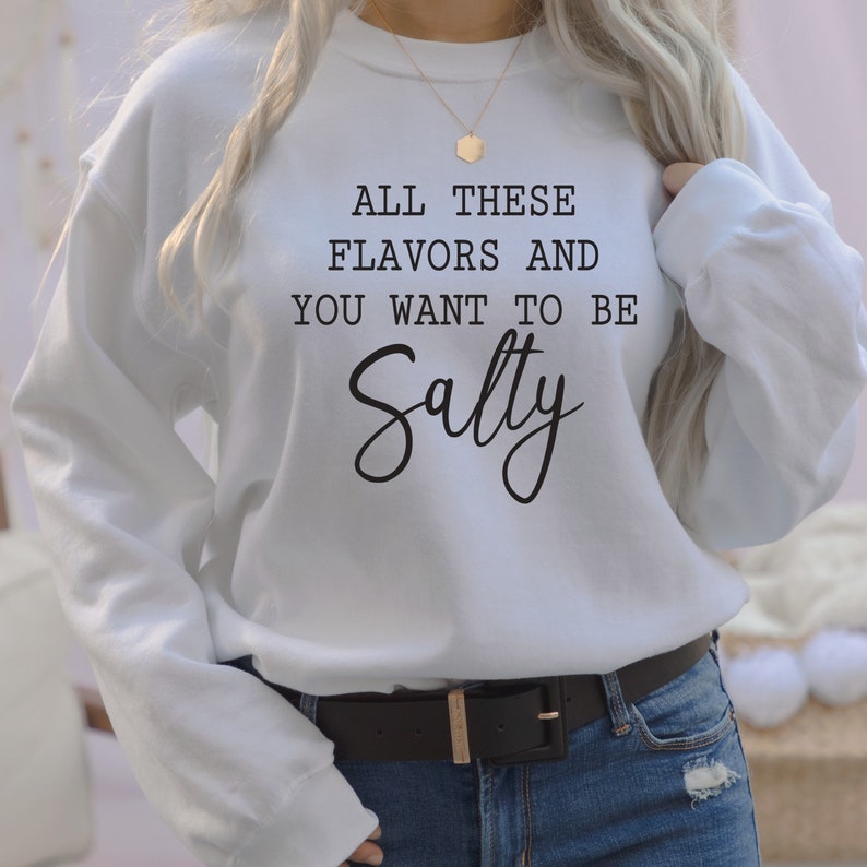 May include: White sweatshirt with black text that reads "All these flavors and you want to be Salty".