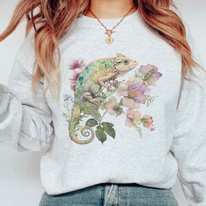 May include: A grey sweatshirt with a green chameleon and pink flowers printed on the front.
