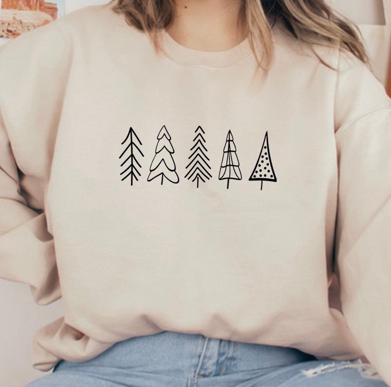 May include: A cream-colored sweatshirt with a black graphic of six stylized Christmas trees.