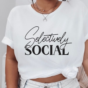 May include: White t-shirt with black text that reads "Selectively Social".