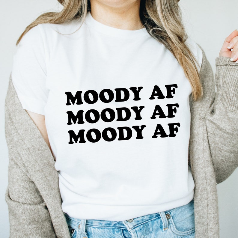 May include: White t-shirt with the text "MOODY AF" repeated three times in black.