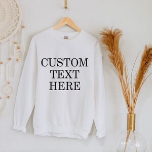 Puede incluir: Sudadera blanca de cuello redondo con el texto "CUSTOM TEXT HERE" impreso en negro en la parte delantera.