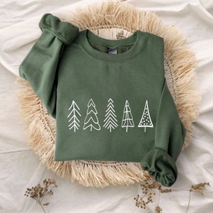 May include: A green sweatshirt with a white graphic of a row of stylized trees. The trees are different shapes and sizes.