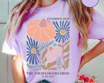 May include: Purple t-shirt with a floral design and the text "Consider How The Wildflowers Grow Luke 12:27".