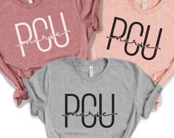 Op de afbeelding: Drie T-shirts met de tekst "PCU nurse" erop gedrukt. De shirts zijn in verschillende kleuren: roze, lichtroze en grijs.