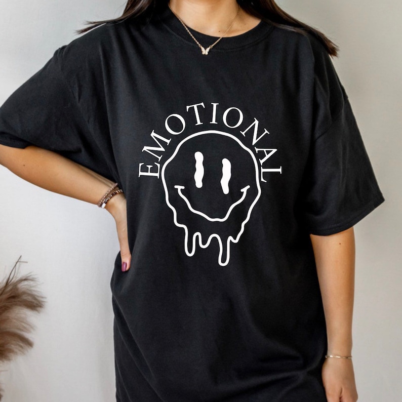 May include: Black t-shirt with a white dripping smiley face and the word "EMOTIONAL" written around it.