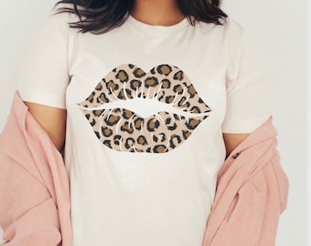 May include: White t-shirt featuring a large leopard print lips design.