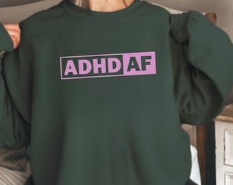 May include: A dark green sweatshirt with the text "ADHD AF" in a pink rectangle.