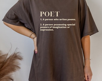 Op de afbeelding: Een bruin T-shirt met het woord "POET" in lichte letters. Daaronder staan twee definities van het woord. Het shirt heeft korte mouwen en een relaxte pasvorm.
