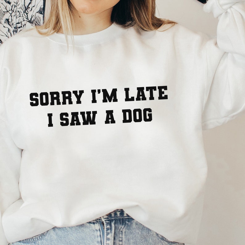 May include: White sweatshirt with black text that reads "Sorry I'm late I saw a dog."