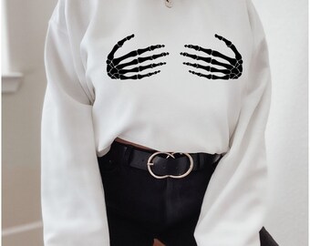 May include: White cropped sweatshirt with a black skeleton hand graphic on the front. The hands are positioned as if they are covering the chest.
