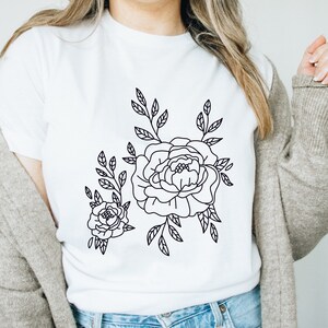 K&ouml;nnte beinhalten: Wei&szlig;es T-Shirt mit einer schwarzen Linienzeichnung eines Blumenstrau&szlig;es mit zwei Rosen und Bl&auml;ttern.