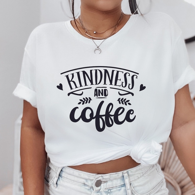 May include: White t-shirt with black text that reads "Kindness and coffee" with a heart and leaf design.