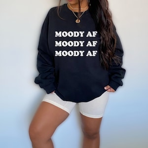 May include: Black sweatshirt with the text "MOODY AF" repeated three times in white.