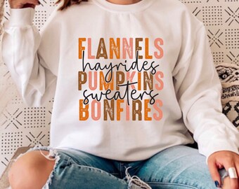 May include: A white sweatshirt with the text "FLANNELS hayrides PUMPKINS sweaters BONFIRES" in brown, orange, and pink lettering.