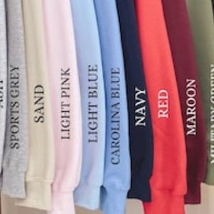Pode incluir: Uma sele&ccedil;&atilde;o de 14 sweatshirts de diferentes cores, incluindo branco, cinza, cinza desportivo, areia, rosa claro, azul claro, azul Carolina, azul marinho, vermelho, castanho, verde militar, verde floresta, chocolate escuro e preto.