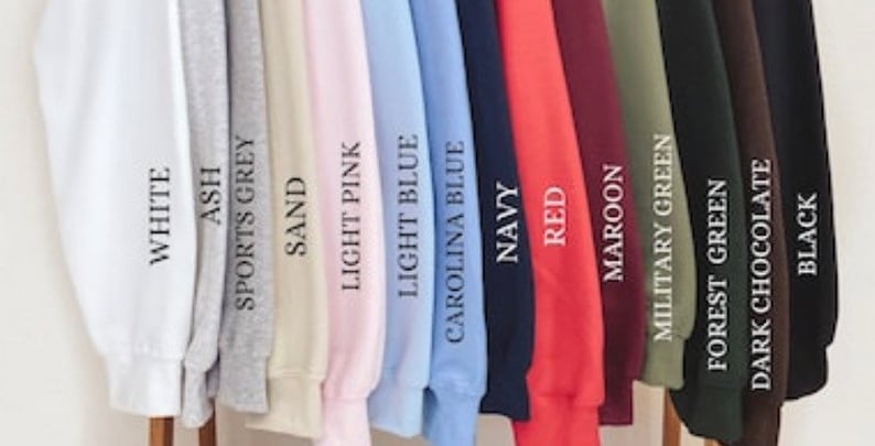 Pode incluir: Uma sele&ccedil;&atilde;o de 14 sweatshirts de diferentes cores, incluindo branco, cinza, cinza desportivo, areia, rosa claro, azul claro, azul Carolina, azul marinho, vermelho, castanho, verde militar, verde floresta, chocolate escuro e preto.