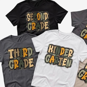 May include: A collection of short-sleeved t-shirts in black, white, and charcoal grey. Each shirt features a central graphic with camouflage-patterned lettering. The text on the shirts reads Second Grade, Third Grade, and Kindergarten.