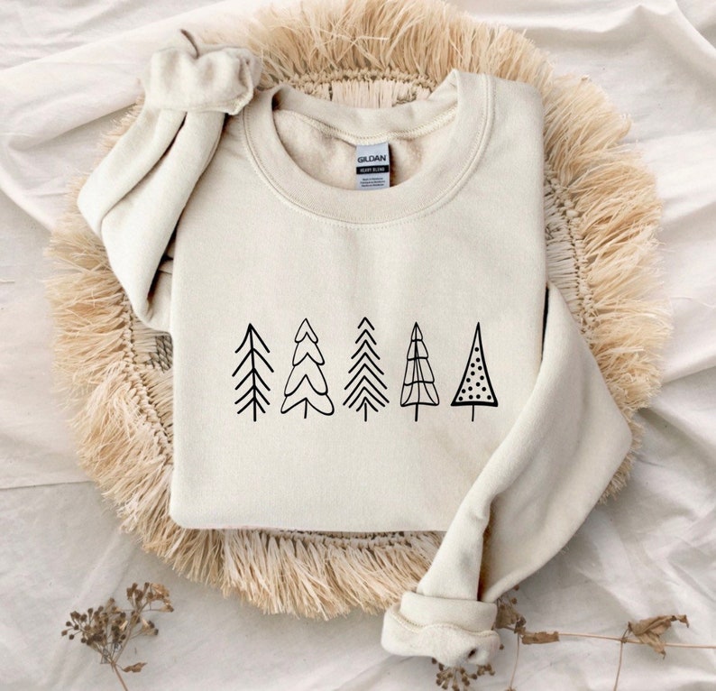 May include: A cream-colored sweatshirt with a black graphic of five stylized Christmas trees.
