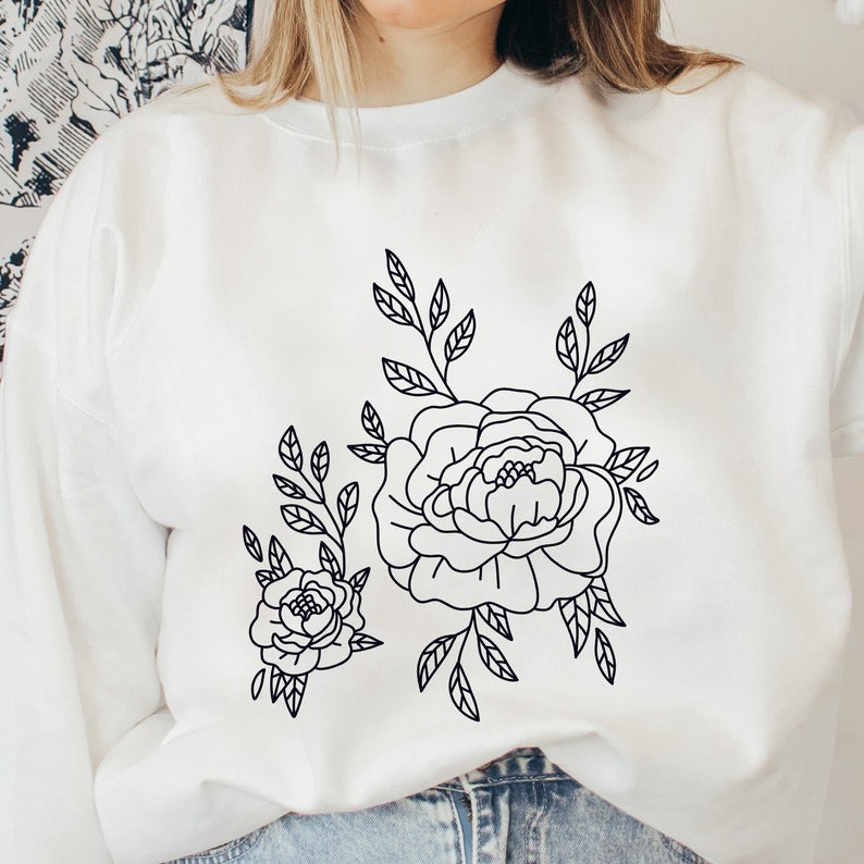 K&ouml;nnte beinhalten: Wei&szlig;es Sweatshirt mit einer schwarzen Linienzeichnung von zwei Blumen und Bl&auml;ttern.