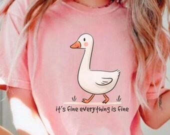 May include: A pink t-shirt featuring a cartoon white goose and the text "it's fine everything is fine".
