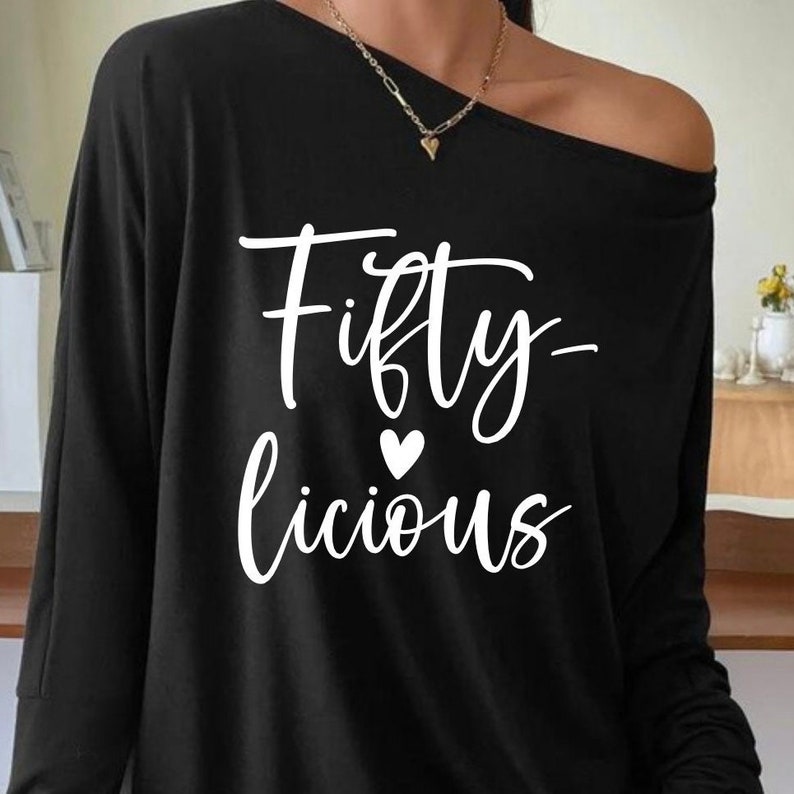 Pode incluir: Camiseta preta de manga comprida com um gr&aacute;fico branco que diz "Fifty-licious" com um pequeno cora&ccedil;&atilde;o.