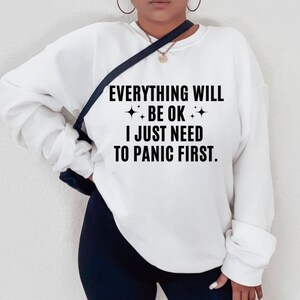 May include: White sweatshirt with the text "Everything will be ok. I just need to panic first."